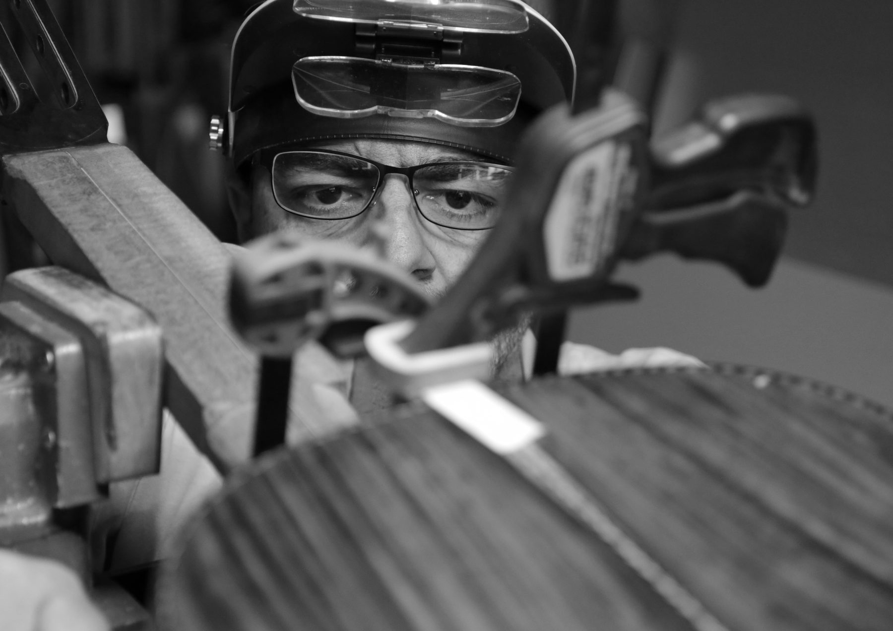 Onofre con visera de lupa, examinando de cerca la tapa de una guitarra en construcción